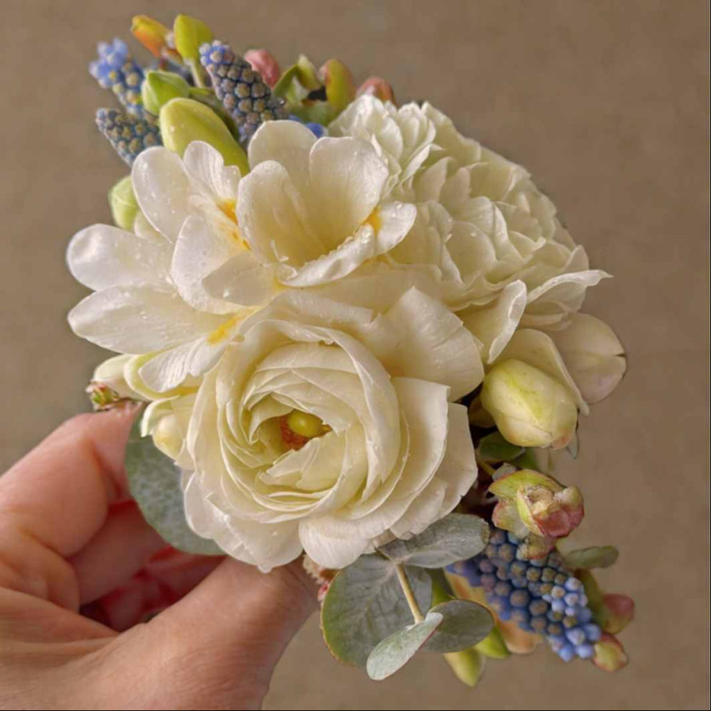 Bouquet of artificial flowers held by a hand against a neutral background