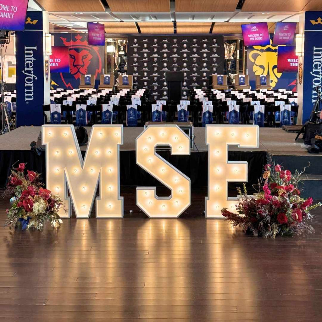 Decorative Marquee Letter setup with 'MSE' letters and floral arrangements in a large indoor space.